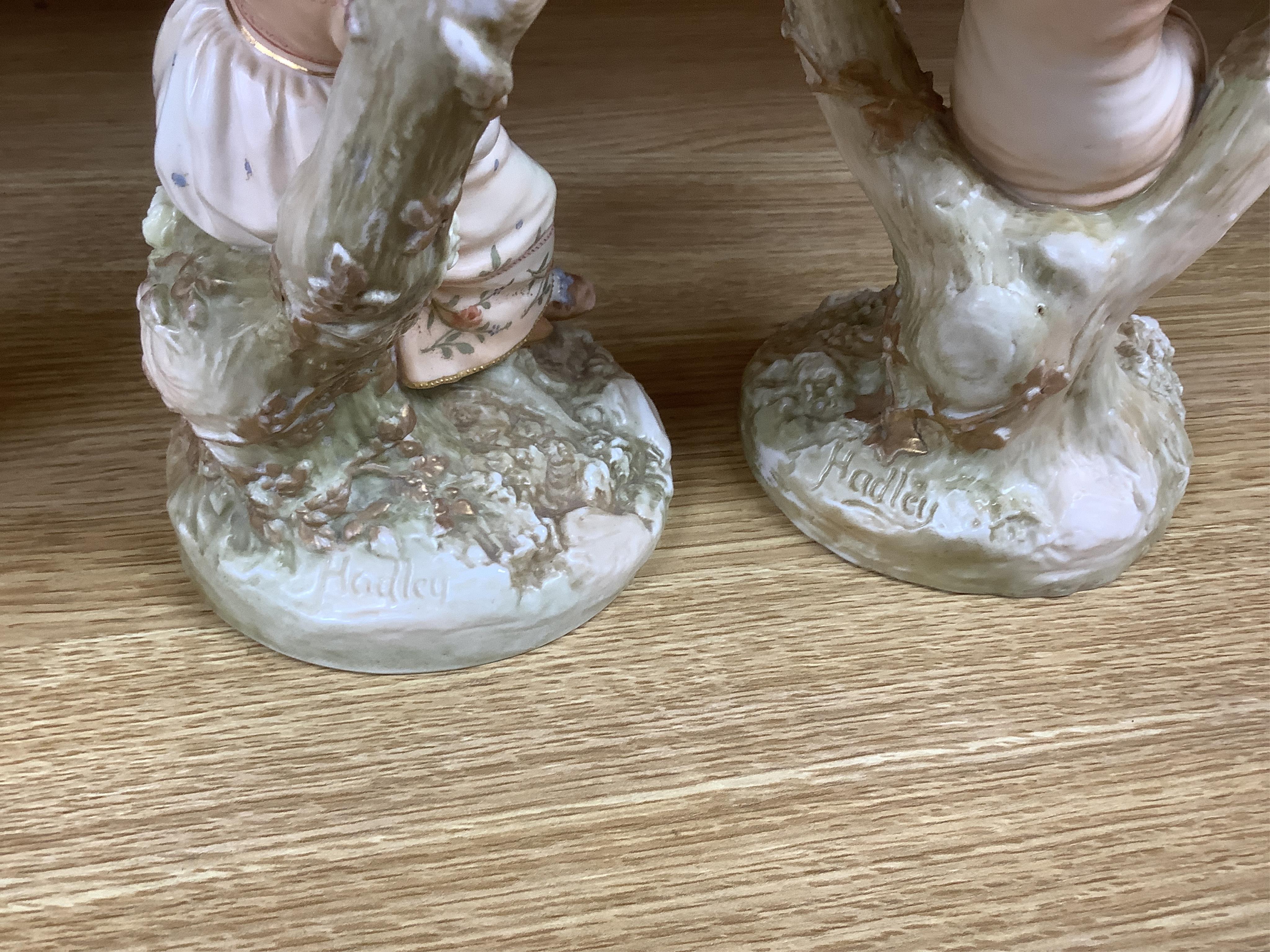 A pair of late 19th century Royal Worcester Kate Greenaway style figural two branch candelabra, modelled by James Hadley 22.5cm high
